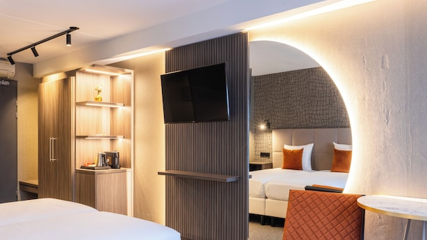 A hotel room with a TV, two beds, a coffee machine, and a small table. - Asteria Hotel Venray (Venray)