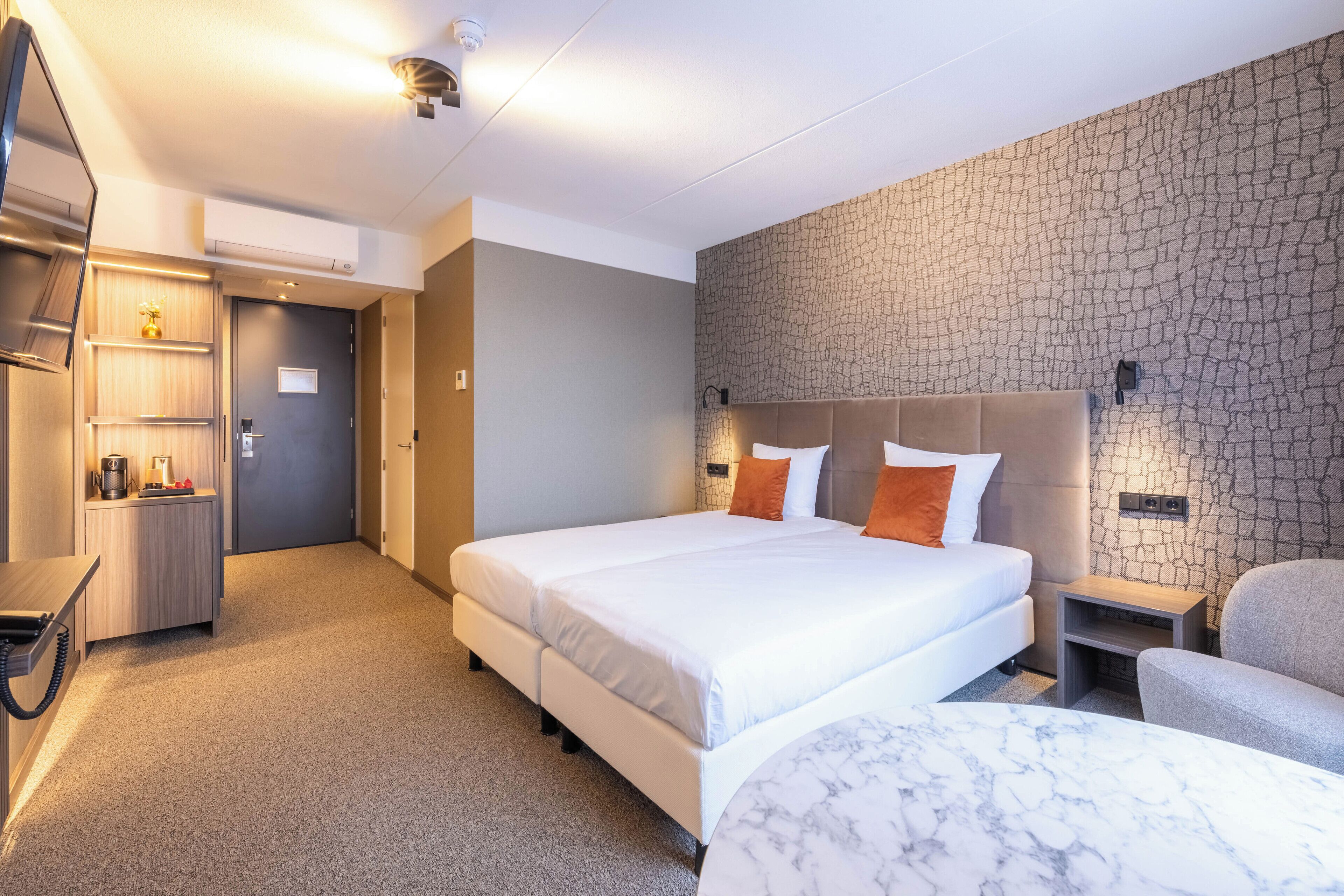 Ein Hotelzimmer mit einem großen Bett, einem Schreibtisch mit Telefon, einem Sessel und einem Marmortisch.
