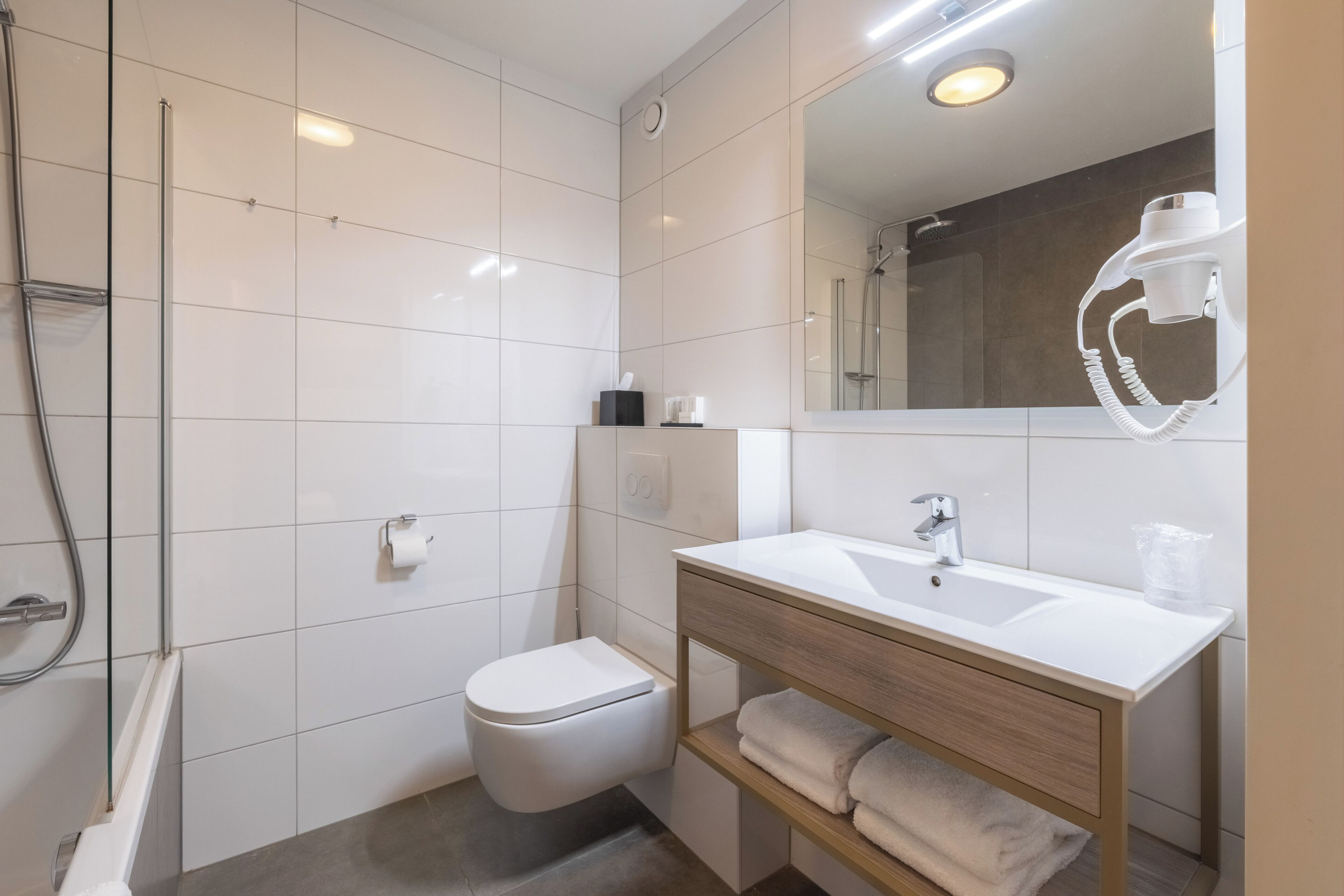 Un baño moderno con inodoro, lavamanos y ducha.