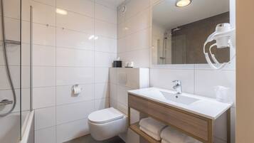 Un baño moderno con inodoro, lavamanos y ducha.