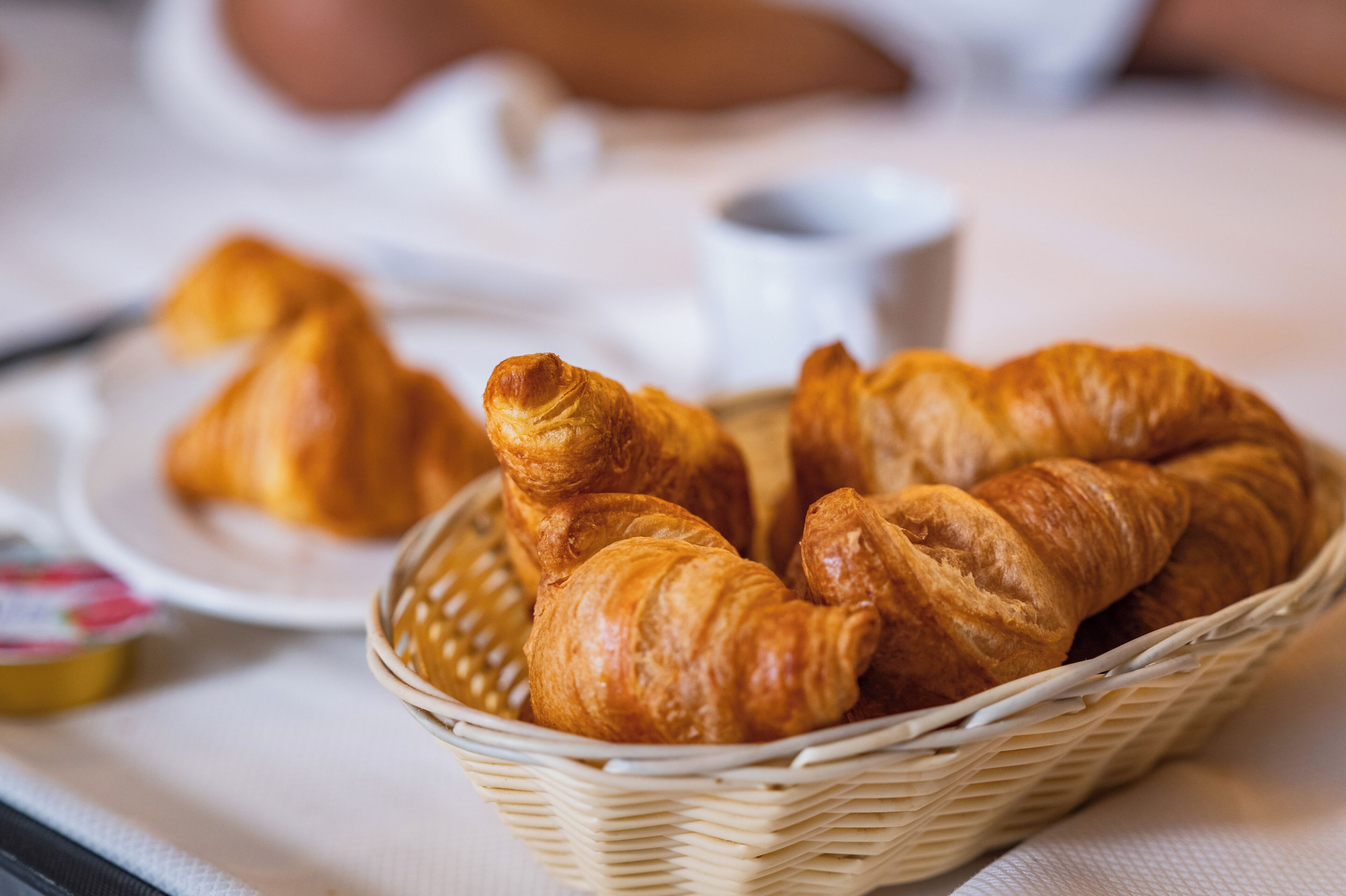 Ein Tablett mit einem Korb voller Croissants.