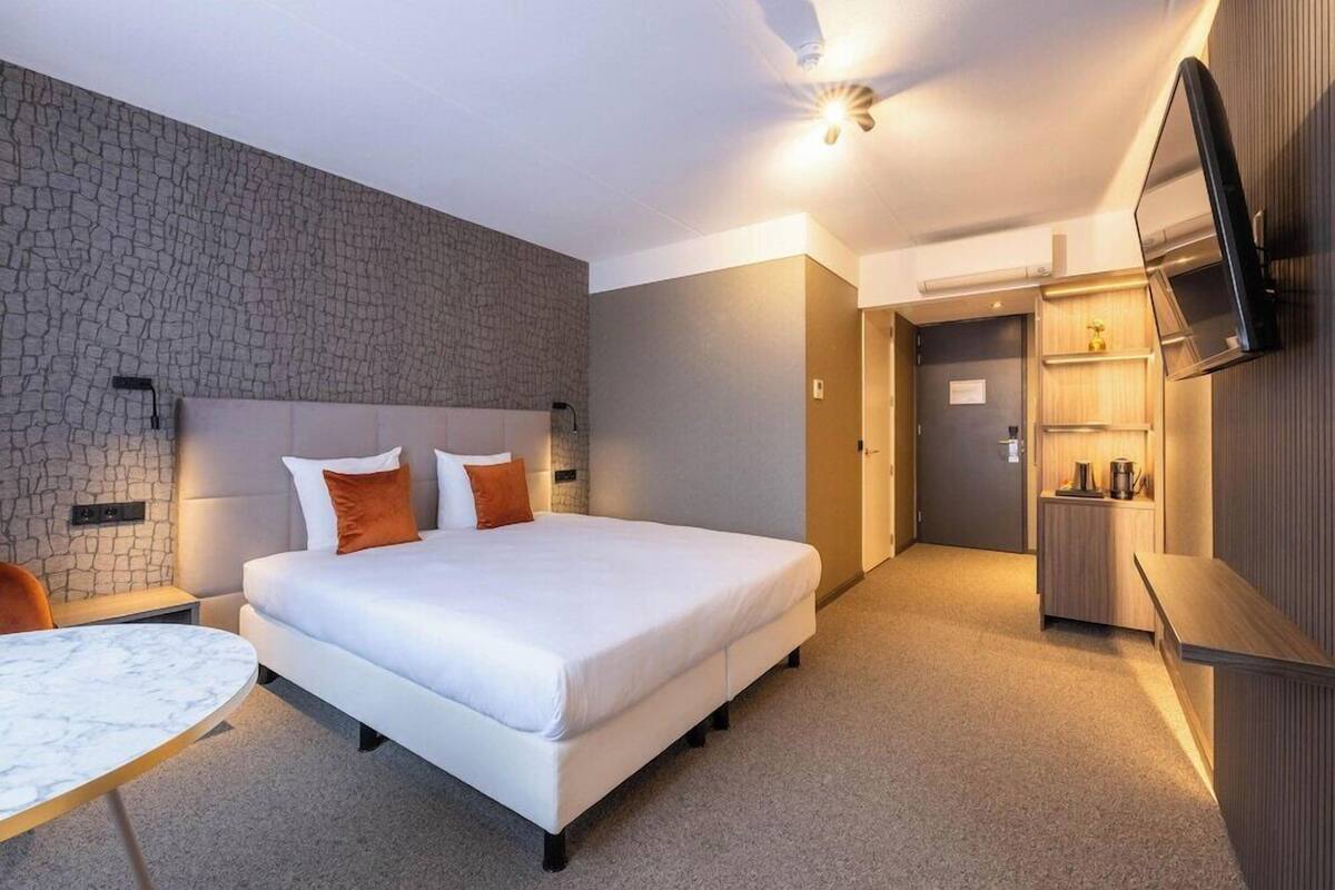 Ein Hotelzimmer mit Bett, Schreibtisch, Fernseher und einer Steinwand.