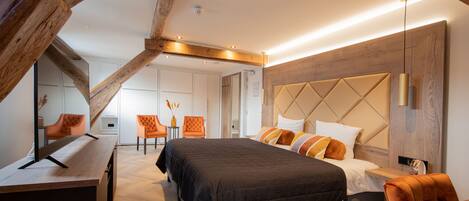 Un dormitorio moderno con una cama grande, vigas de madera, un escritorio y una mesa de comedor.