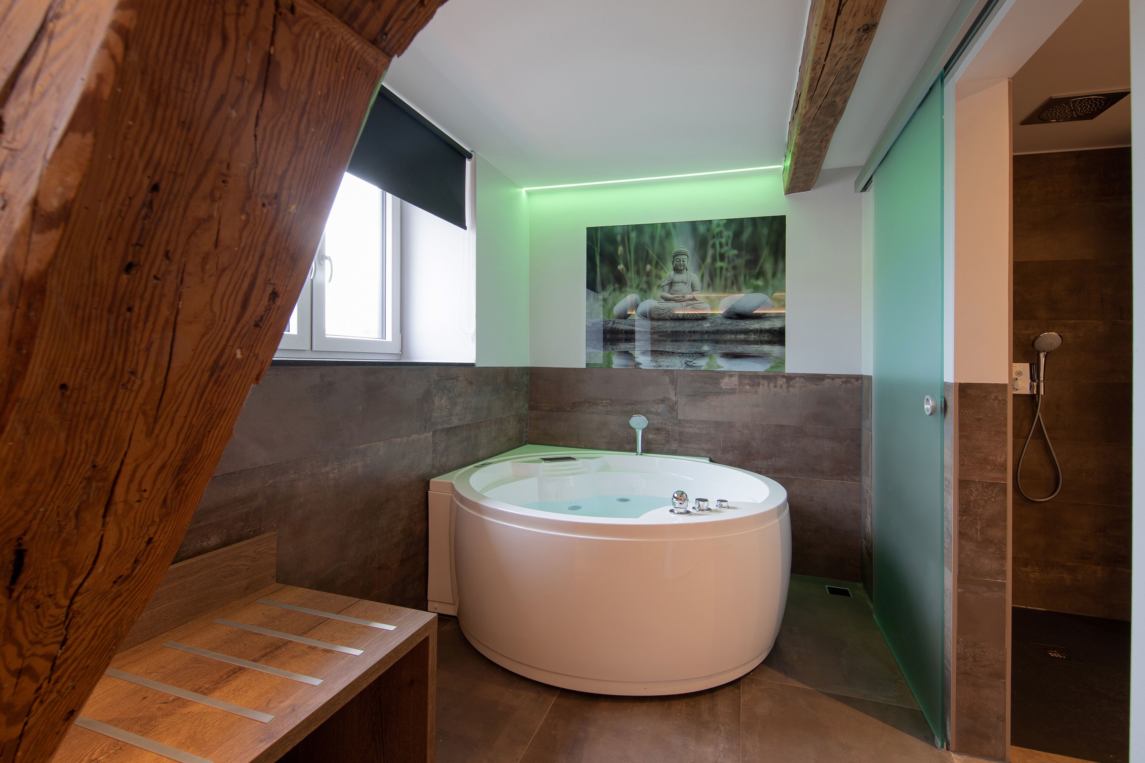 A modern bathroom with a freestanding bathtub, a wooden bench, and a large window.