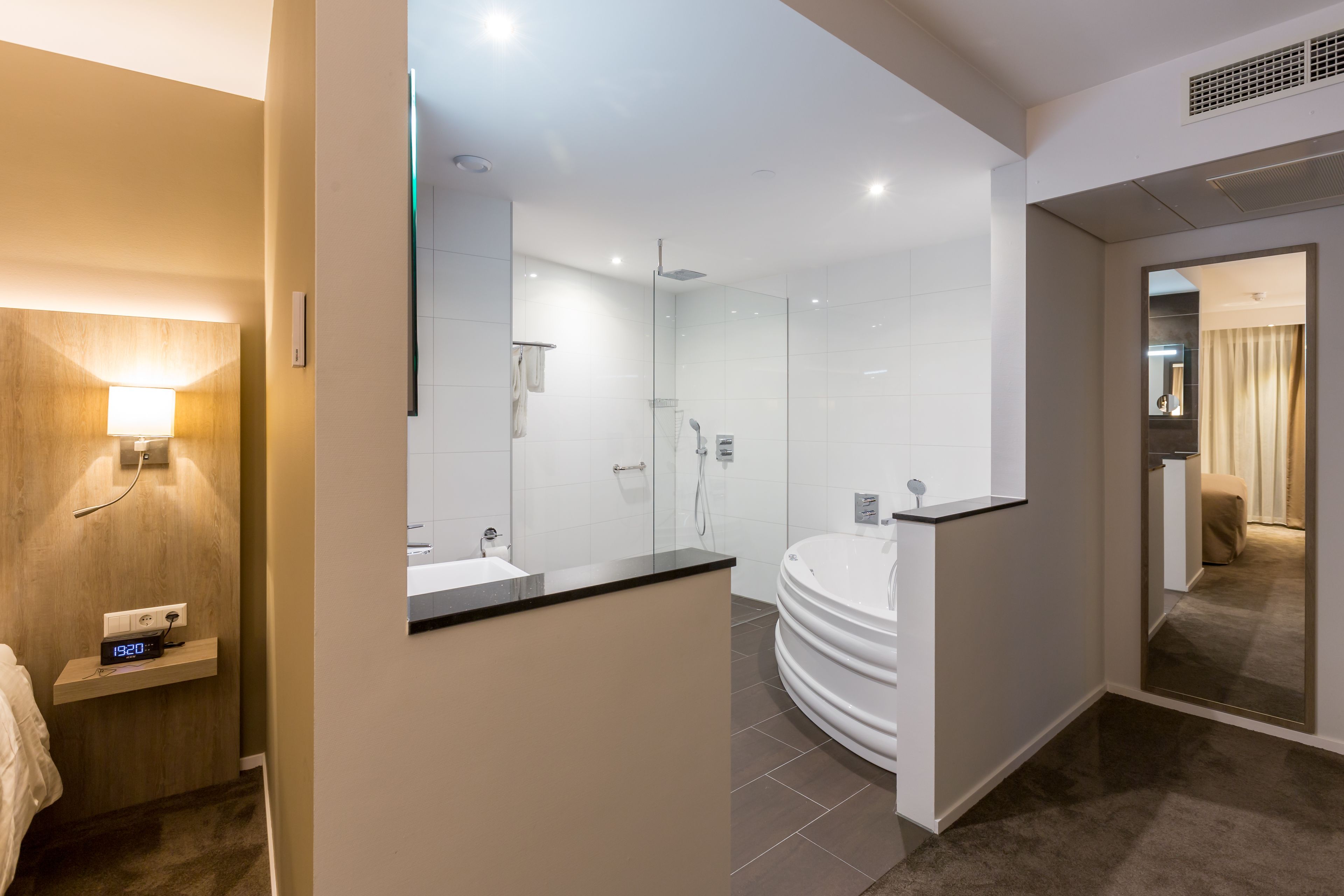 A modern bathroom with a large bathtub, a glass shower enclosure, and a vanity with a mirror.