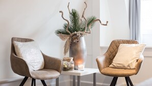 Una habitación moderna con dos sillones de cuero, una mesita pequeña, una planta decorativa y una vela.