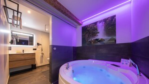 Un baño moderno con una bañera grande, un tocador de madera, un espejo y un lavamanos empotrado.