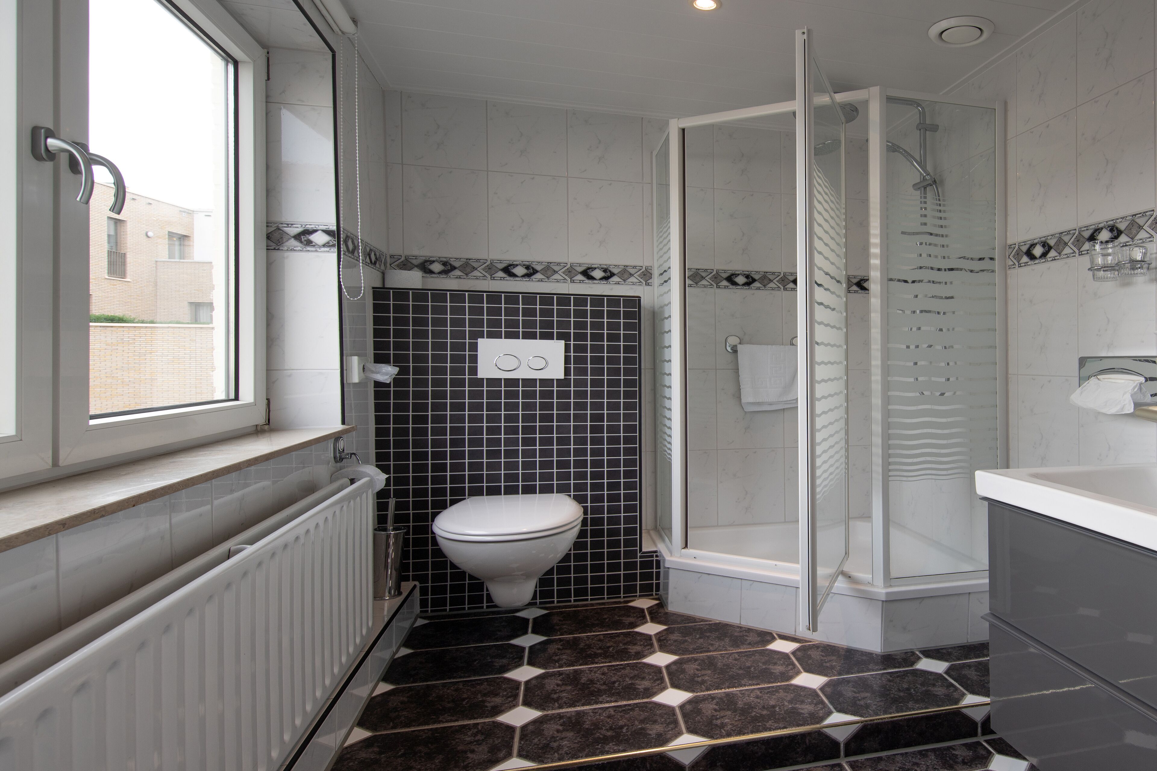 A bathroom with a toilet, a shower, and a window.