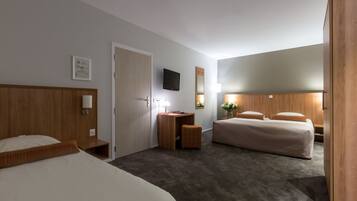 A hotel room with two beds, a desk, a television, and a mirror.