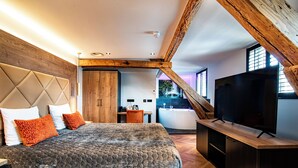 Un dormitorio moderno con una cama grande, vigas de madera en el techo, un televisor y vistas al exterior.