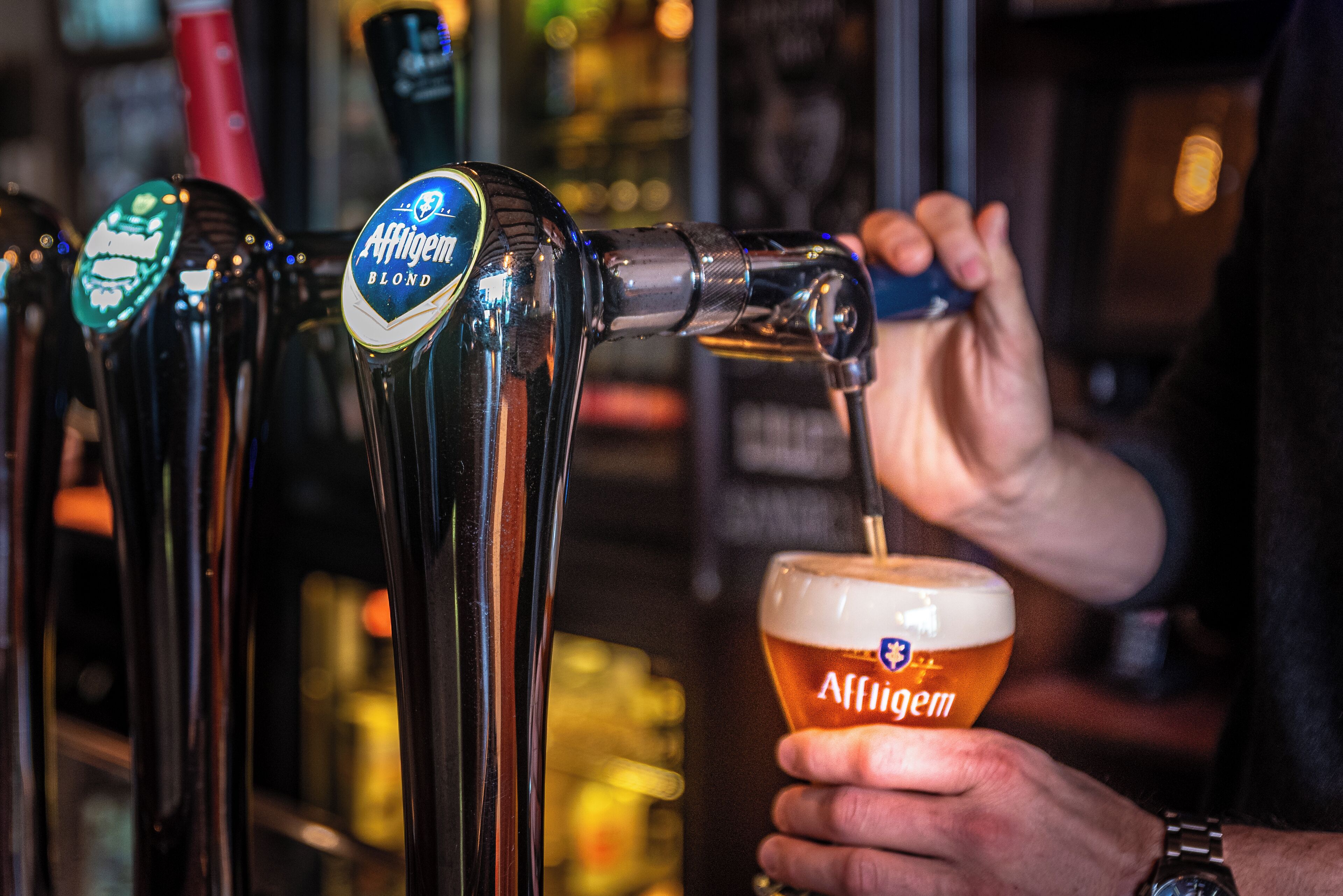 Eine Bar mit Zapfhähnen und einer Person, die Bier in ein Glas einschenkt.