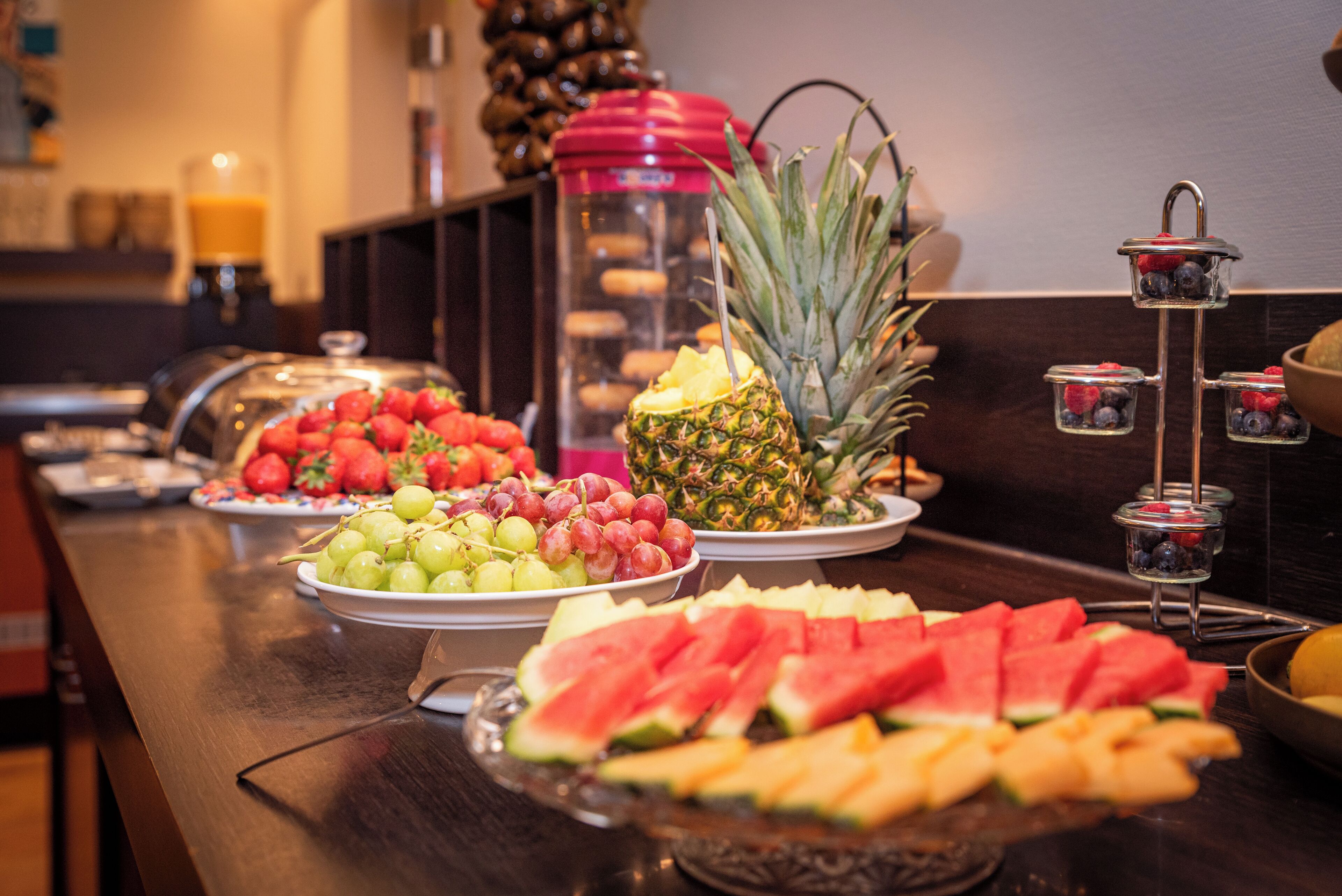 Een buffet met verschillende soorten fruit en een sapautomaat.