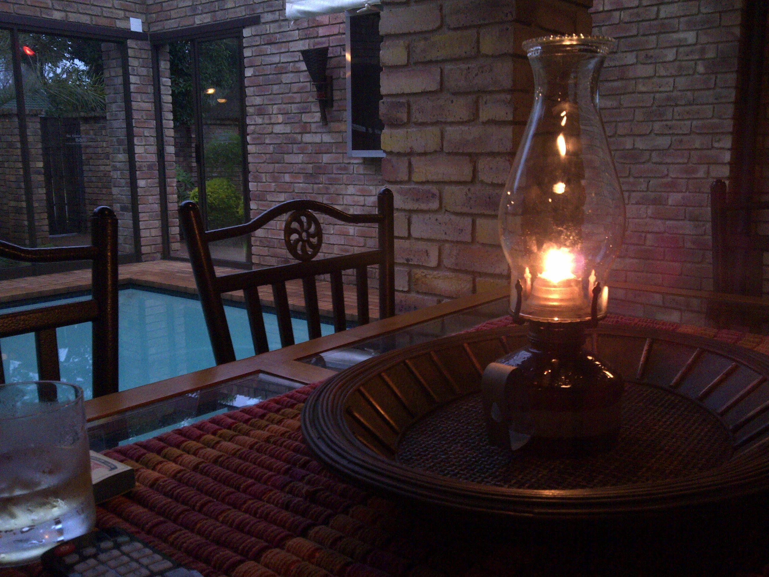 A poolside area with a glass table, a chair, and a lit candle.