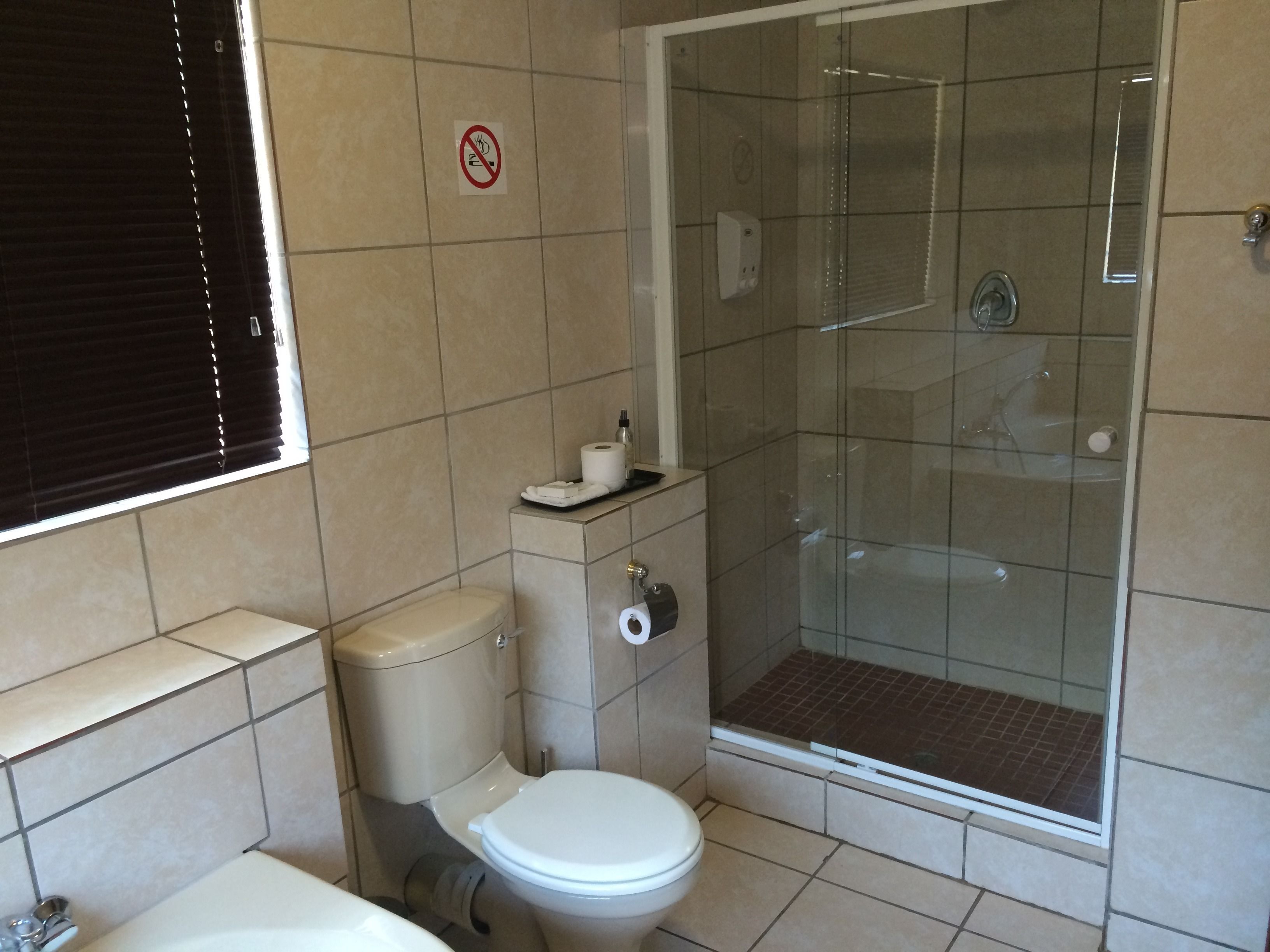 Un baño con inodoro, cabina de ducha y soporte para papel higiénico.
