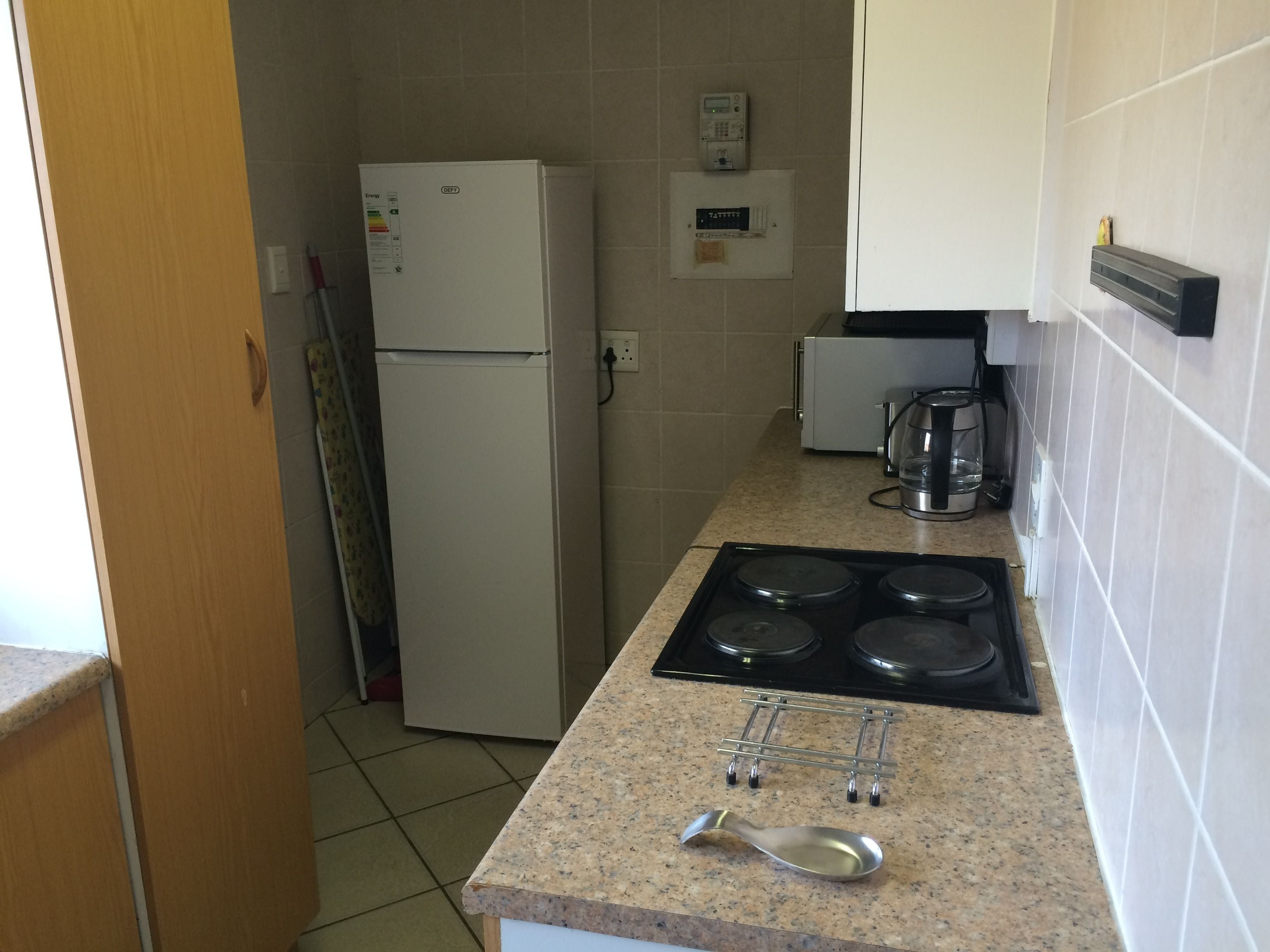 Una cocina compacta equipada con refrigerador, cafetera y estufa.