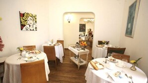A dining area with round tables, white tablecloths, and wooden chairs. - Trastevere Relais (Rome)