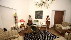A living room with a chandelier, a painting, a table with decorative items, and patterned furniture. - Trastevere Relais (Rome)