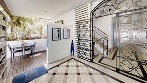 A modern interior with a staircase, a dining area, and a view of palm trees outside. - Silkari The Pavilions Port Douglas (Port Douglas)