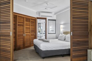 Une chambre d’hôtel avec un lit, un ventilateur de plafond, un miroir et des panneaux de bois.