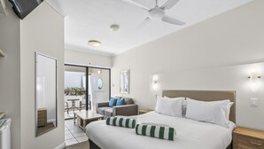 A hotel room with a bed, bedside tables, a ceiling fan, and a view through a sliding door to an outdoor area. - Silkari The Pavilions Port Douglas (Port Douglas)
