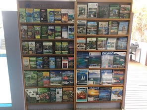 A bookshelf filled with travel books, including titles like "Daintree Rainforest" and "Crocodiles in the Wild". - Silkari The Pavilions Port Douglas (Port Douglas)