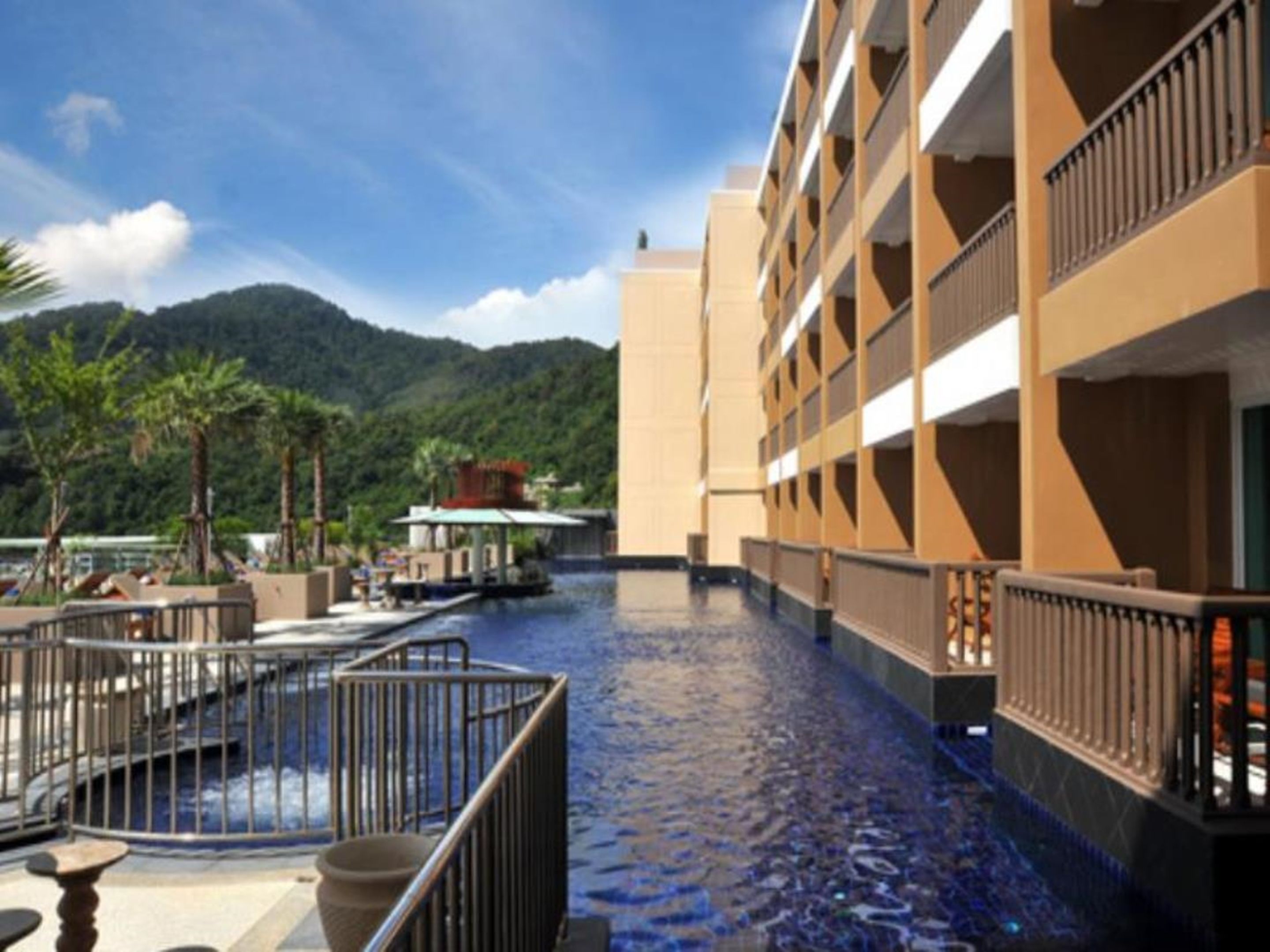 Un hotel con area piscina, vista sulle montagne e un edificio con numerosi balconi.