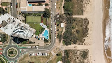 An aerial view of a coastal area with a road, a swimming pool, and a beach.