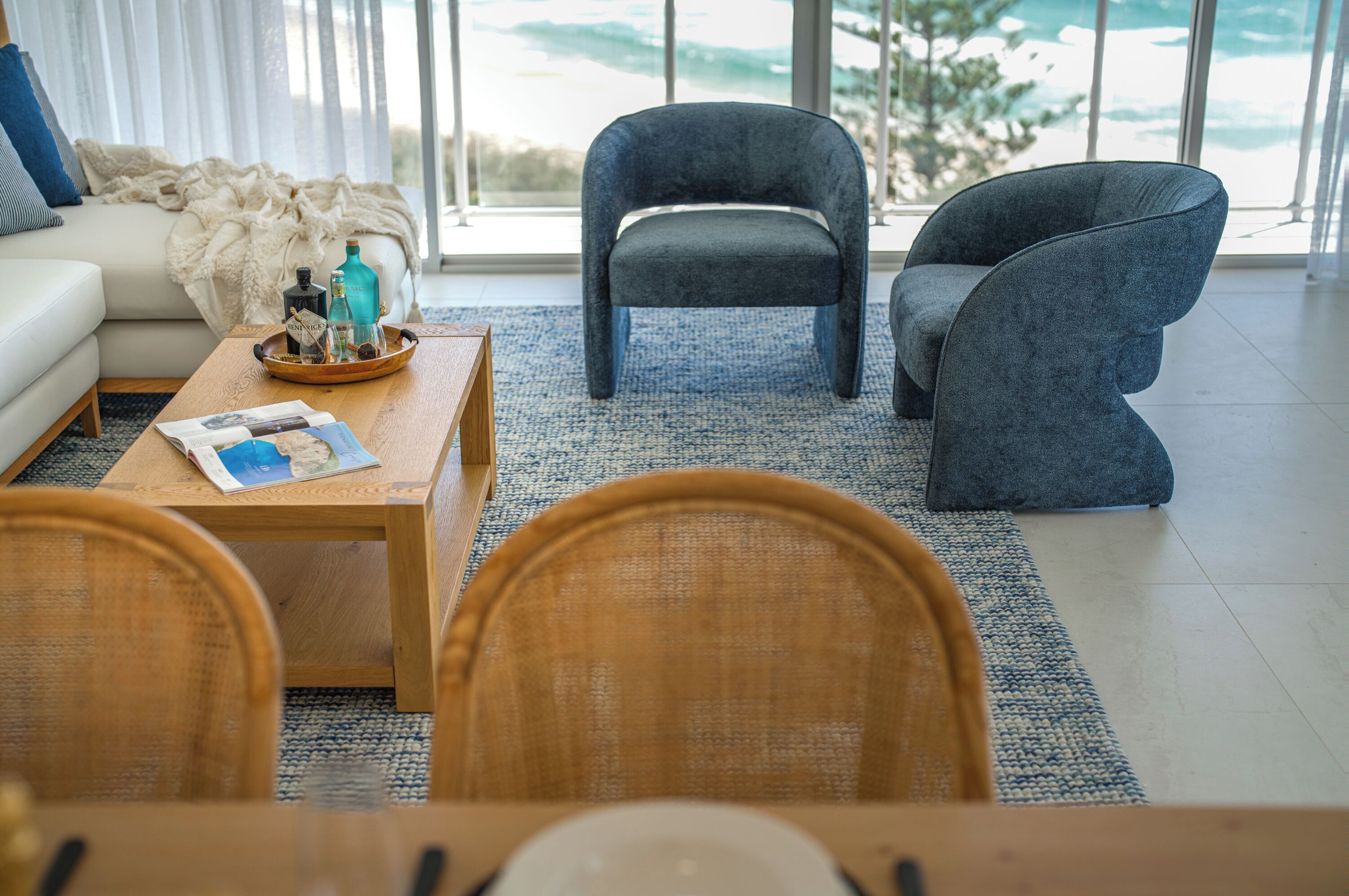 Una sala de estar moderna con un sofá, dos sillones, una mesa de centro y vistas al exterior.