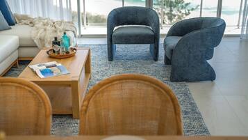 Una sala de estar moderna con un sofá, dos sillones, una mesa de centro y vistas al exterior.