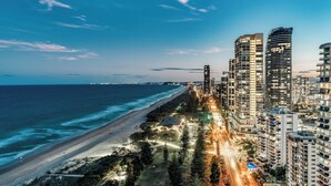 Un paisaje urbano costero con rascacielos, una playa y una calle bien iluminada.