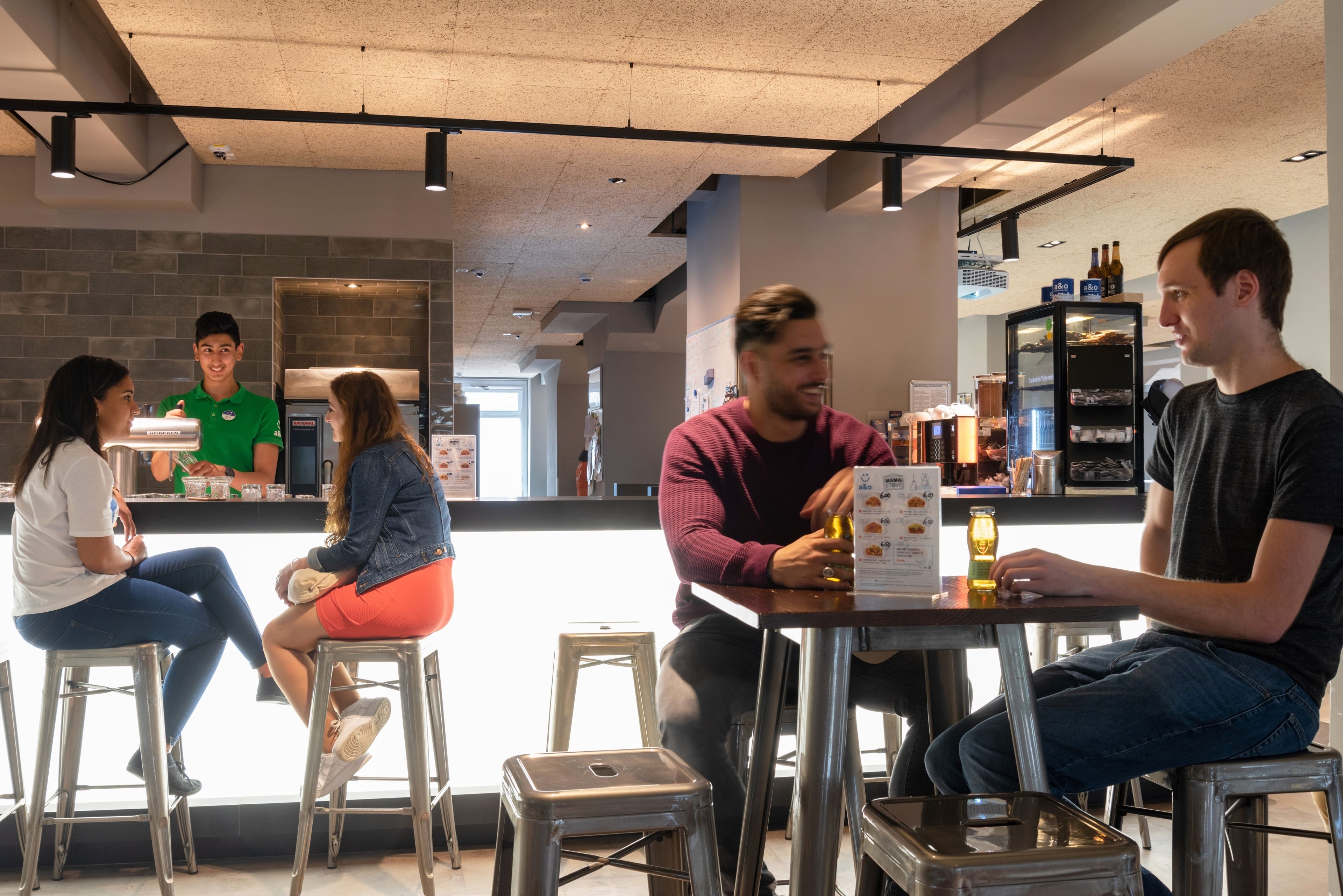 A modern bar area with metal stools and a counter.
