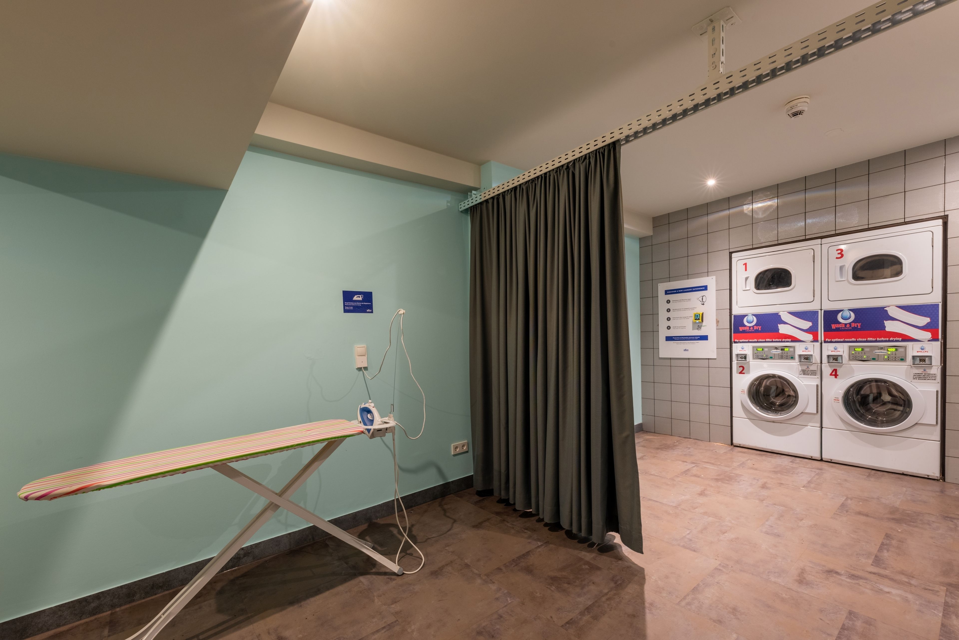 Un espace buanderie comprenant un étendoir, un lave-linge et un mur utilitaire avec un panneau indicateur.
