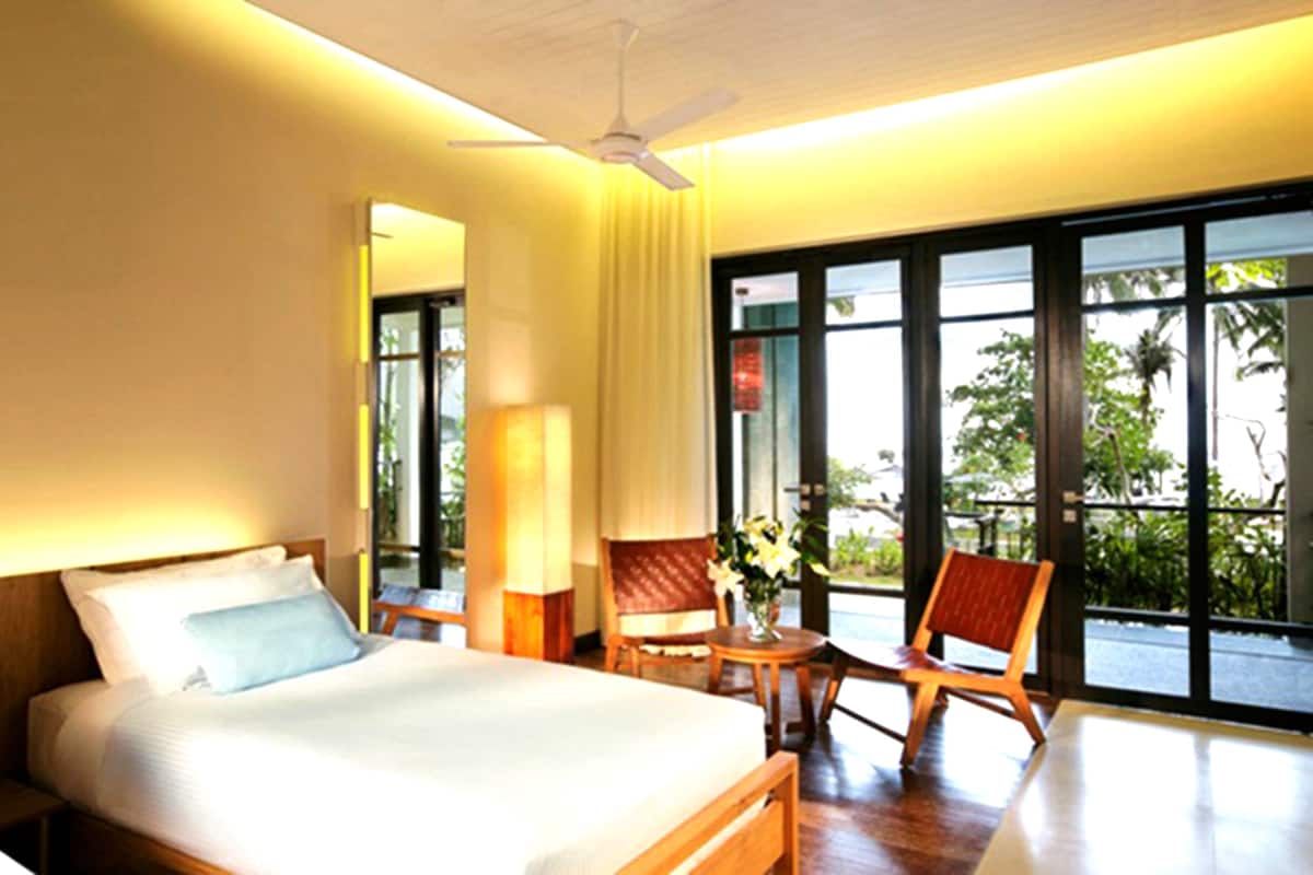 Ein Hotelzimmer mit einem Bett, zwei Stühlen, einem Tisch und großen Fenstern.