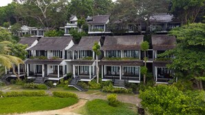 Un hotel de varios pisos con balcones, rodeado de abundante vegetación.