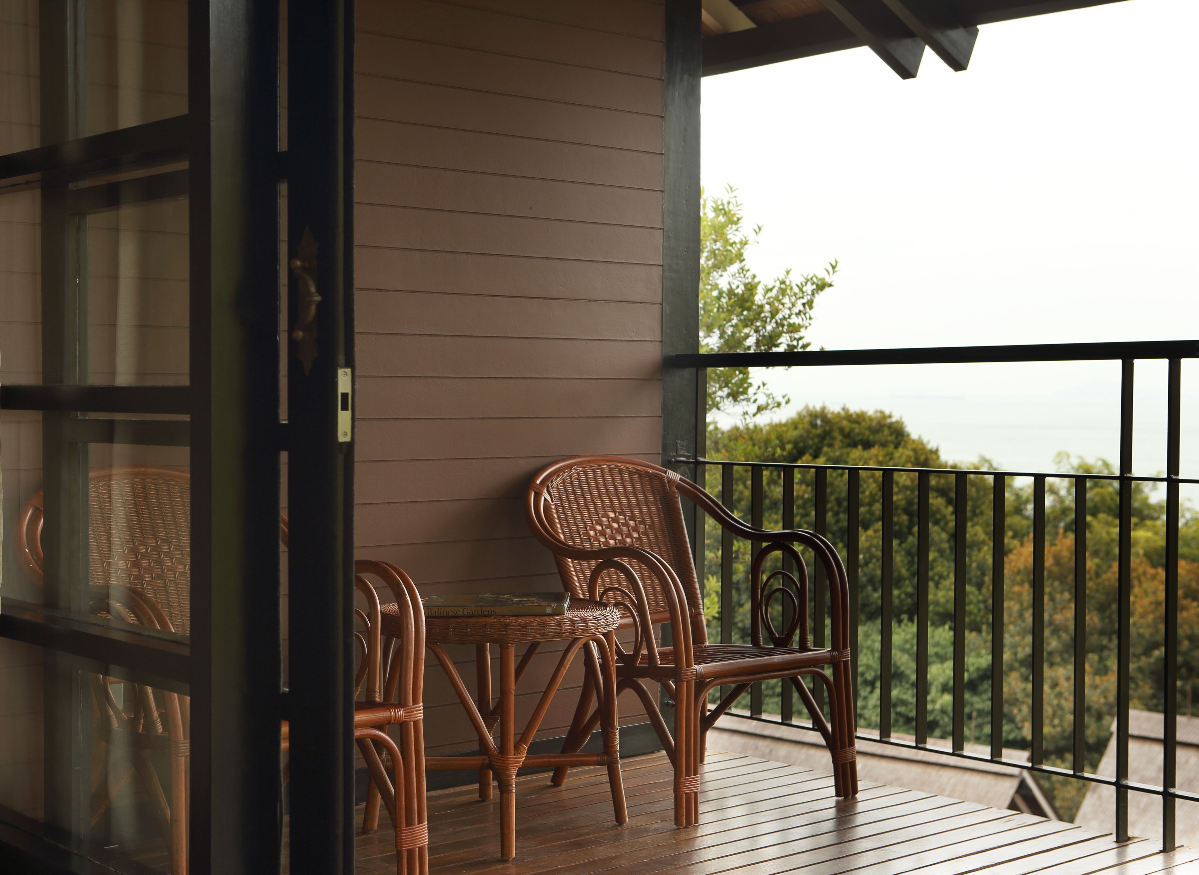 A wooden deck with wicker furniture and a view of trees.