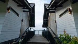 Una escalera conduce a un edificio de diseño moderno, con barandilla de metal y vista al cielo.