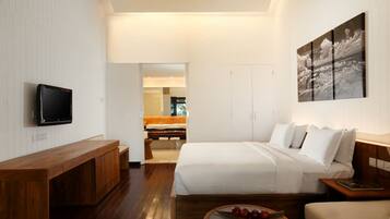 A modern hotel room with a wooden bench, a bed with white linens, a flat-screen TV mounted on the wall, and a painting above the bed.