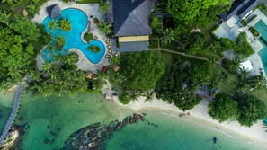 An aerial view of a resort with a large swimming pool, palm trees, and a beach area. - Turi Beach Resort (Batam)