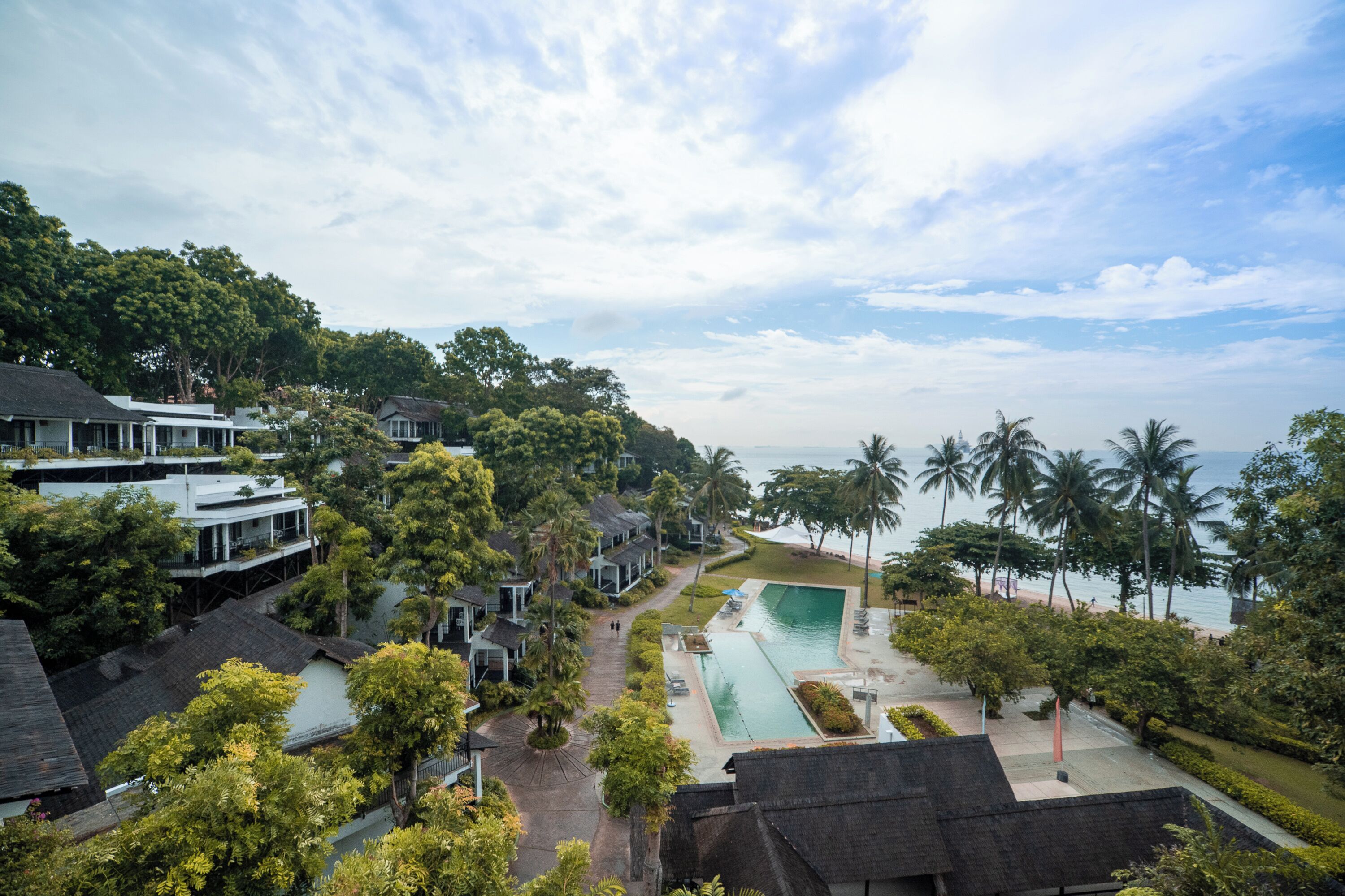 Ein Resort mit Pool, Palmen und Meerblick.