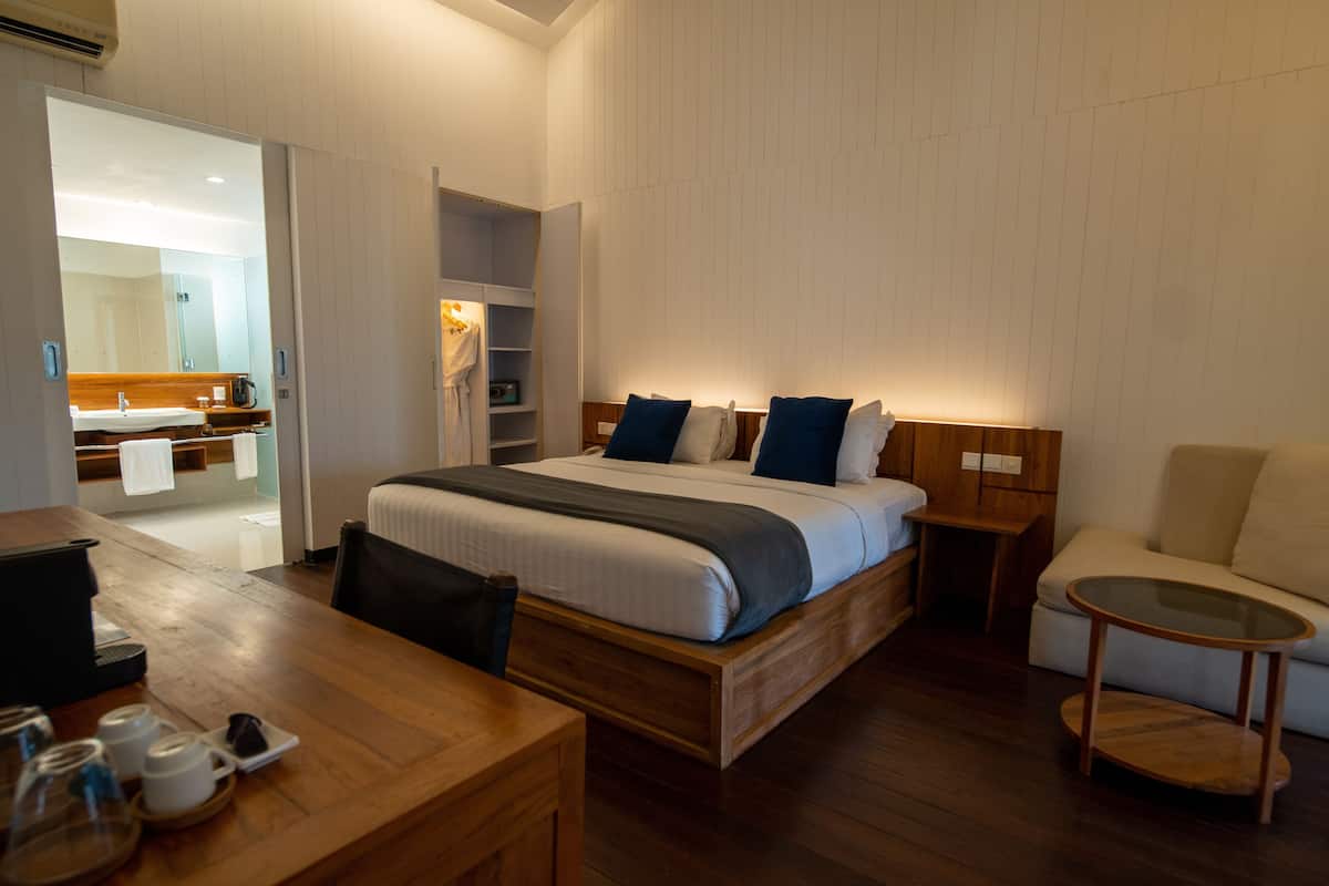 Ein modernes Hotelzimmer mit einem Holzbett, einem kleinen Tisch mit Tassen, einer Couch und einem Glastisch.