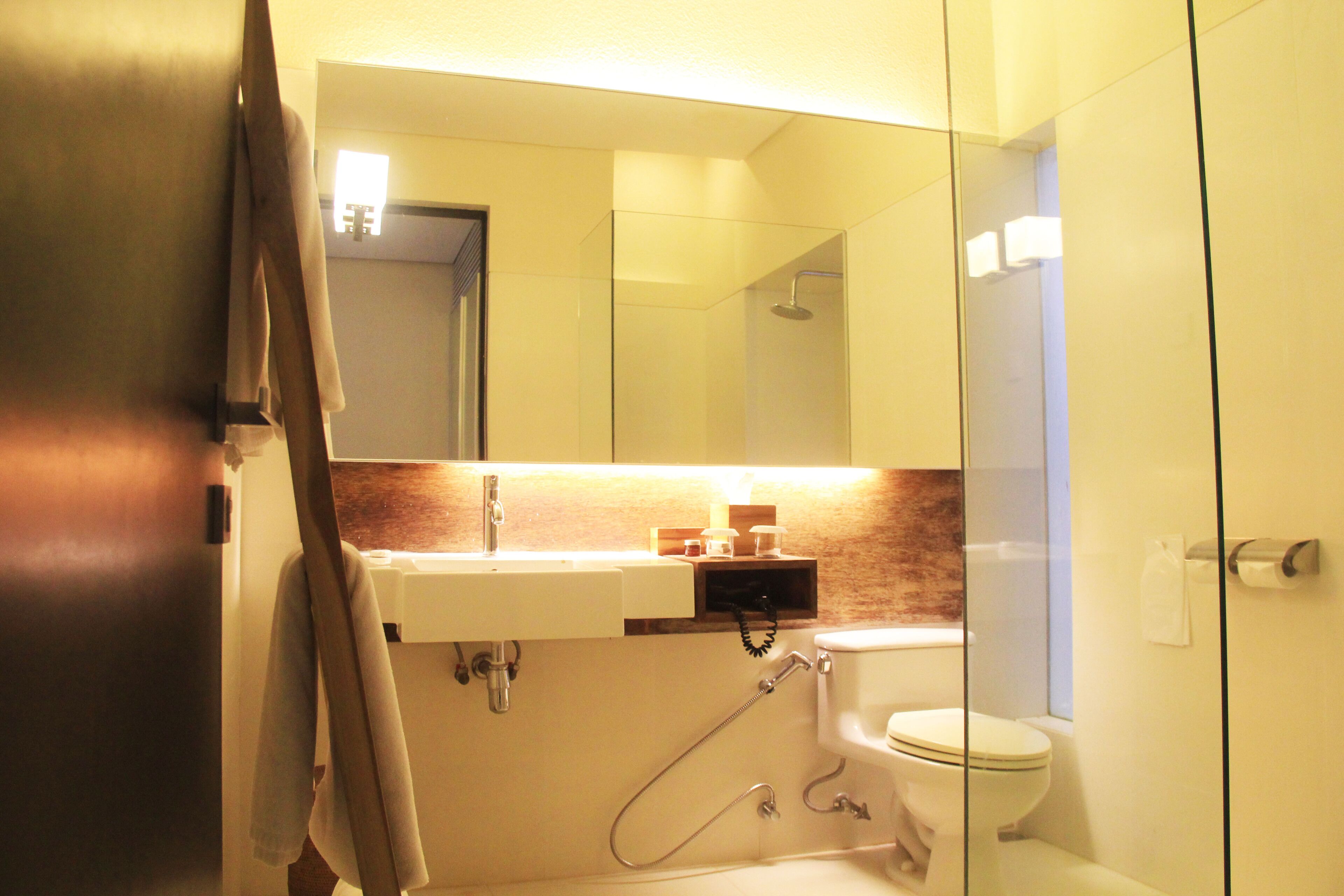 A bathroom with a glass shower enclosure, a white sink, and a toilet.
