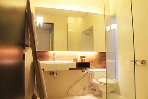 A bathroom with a glass shower enclosure, a white sink, and a toilet.