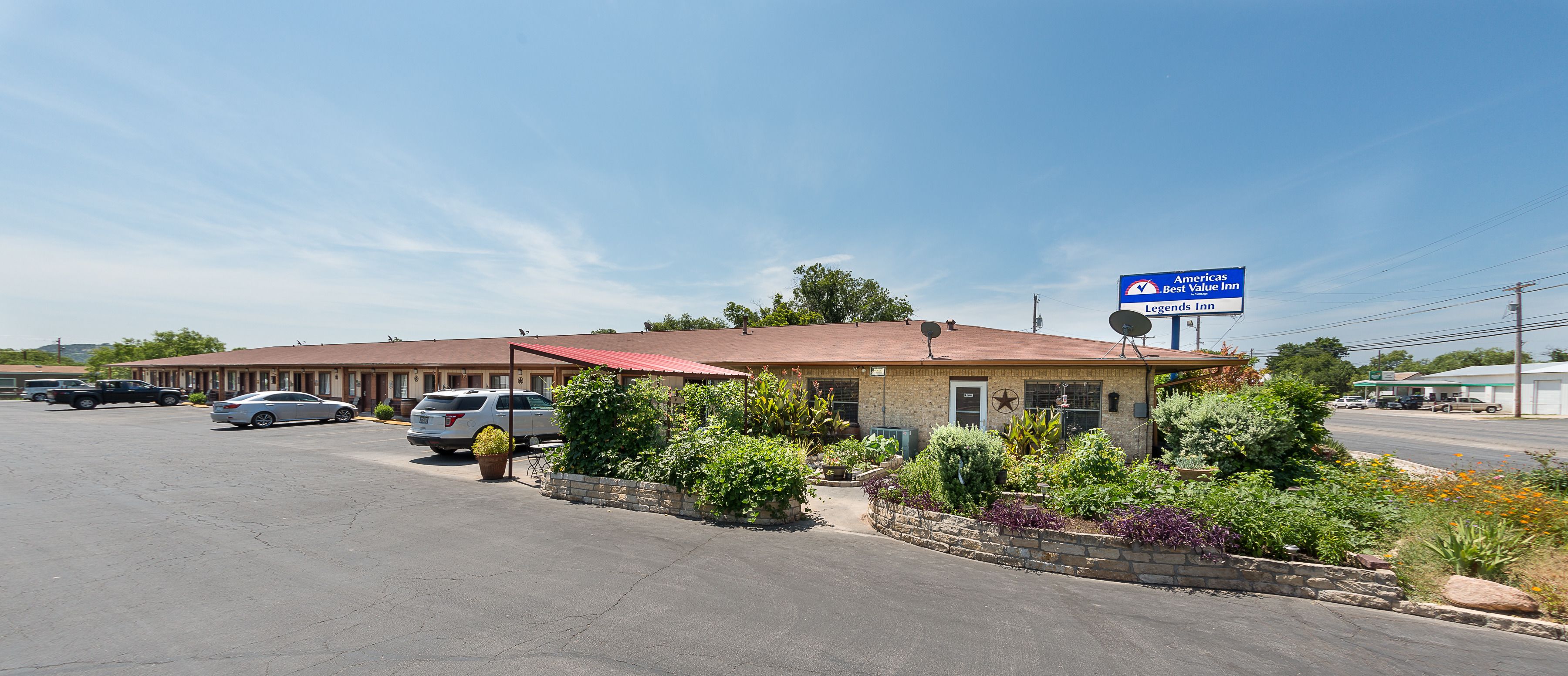 A motel with a red roof, a parking lot, and a sign indicating it is a Best Value Inn.