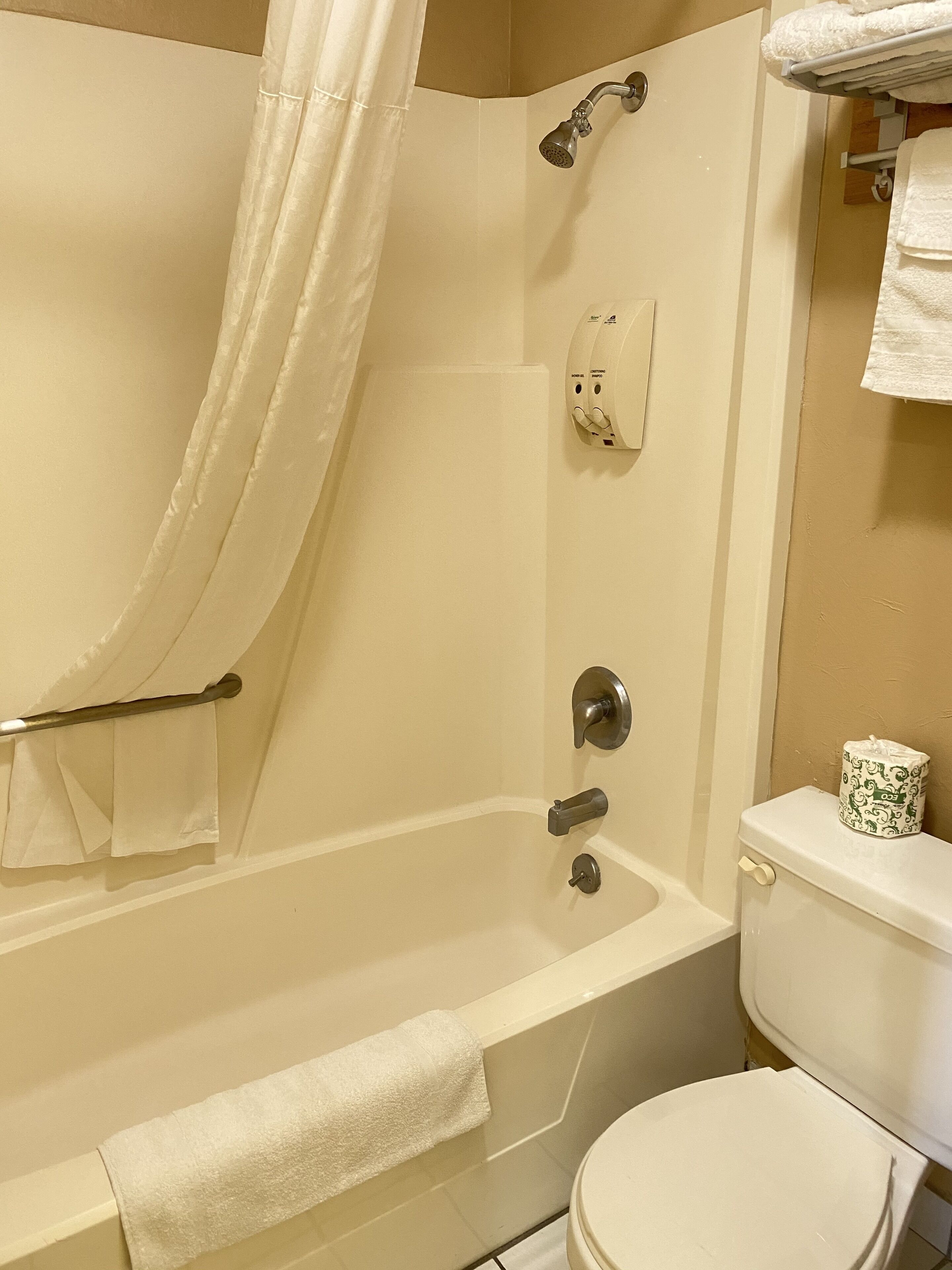 Een badkamer met een bad, toilet en douche.