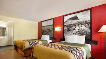 Een hotelkamer met twee bedden, een rode accentmuur en een zwart-wit landschapsfoto in een lijst.