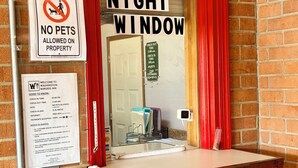 A hotel entrance with a 'No Pets Allowed' sign, a 'Night Window' sign, and a 'Key Drop' box.