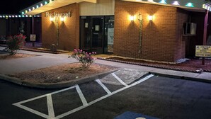 A building with a brick facade, a wheelchair-accessible parking space, and a sign for 'Restaurant' above the entrance.