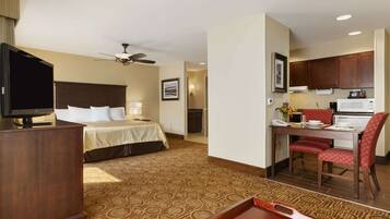 A hotel room with a bed, a desk, a television, and a kitchenette.