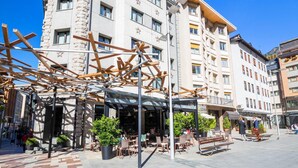 A hotel with a modern design, featuring a covered outdoor seating area with chairs and potted plants. - Hotel Tudel (Escaldes-Engordany)