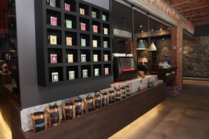 Interior de una cafetería con una exhibición de sacos de café y una máquina de café.